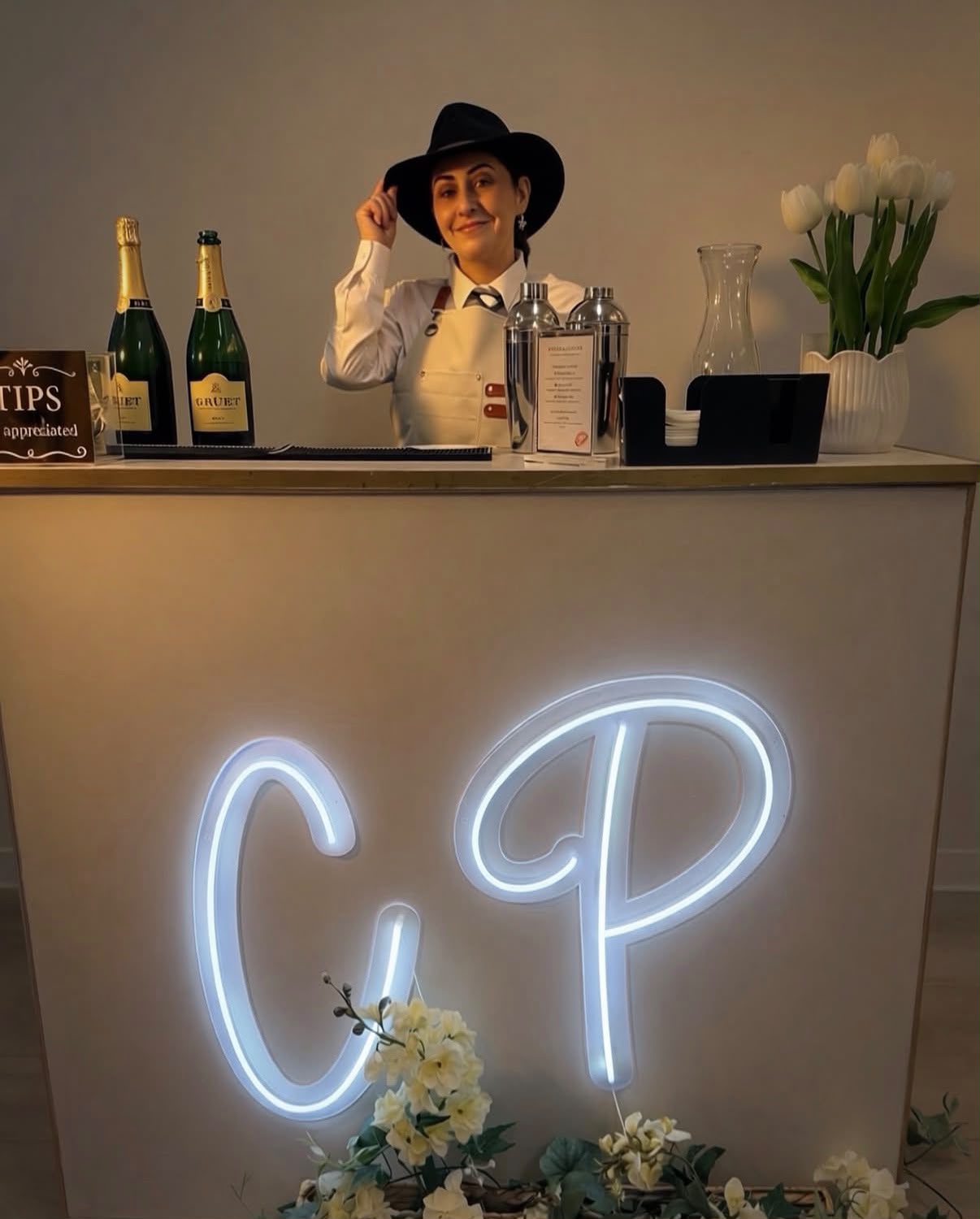 Champagne Problems mobile bar with a glowing CP neon sign, white florals and Gruet champagne at an indoor celebration