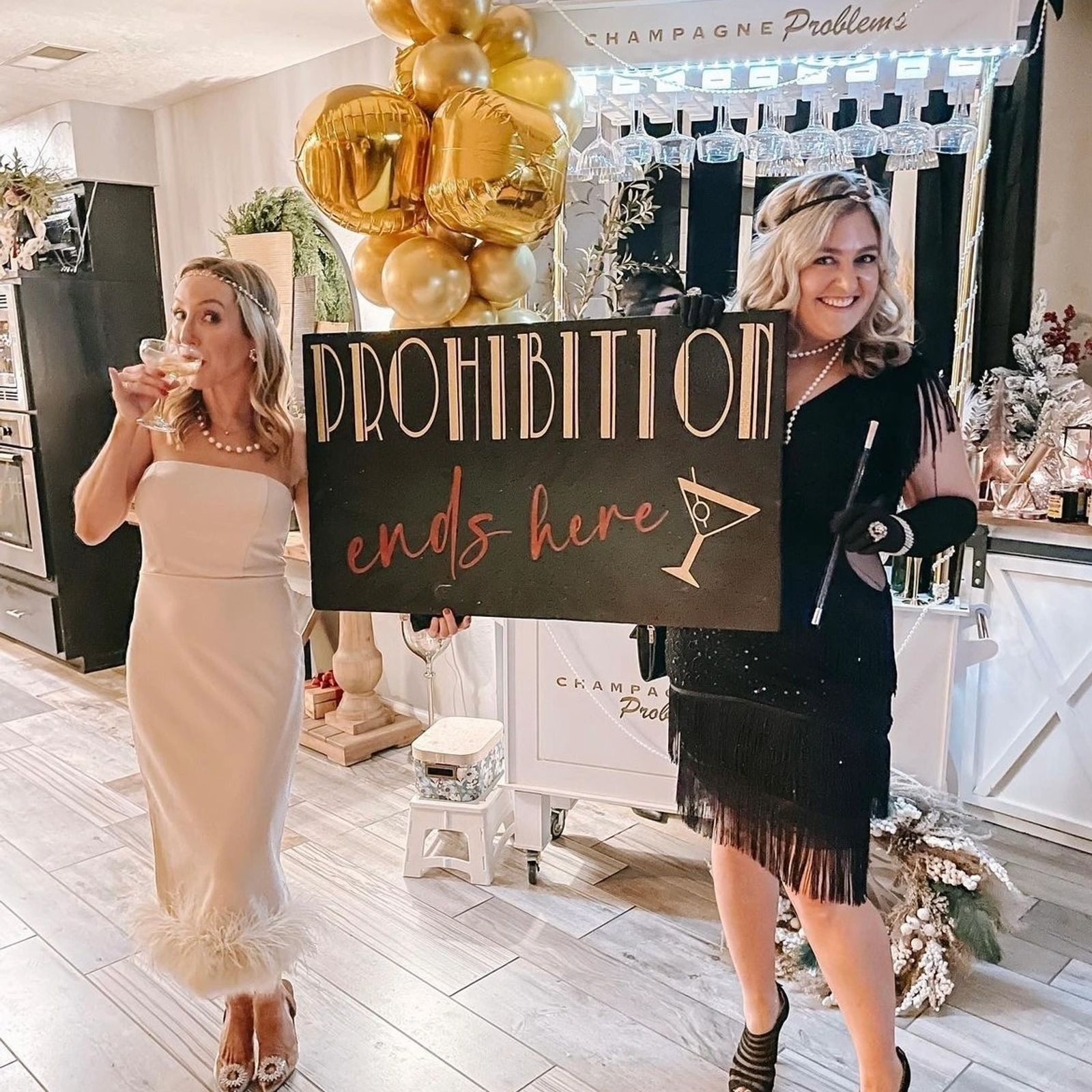 Guests celebrating at a Prohibition-themed party with a gold balloon backdrop