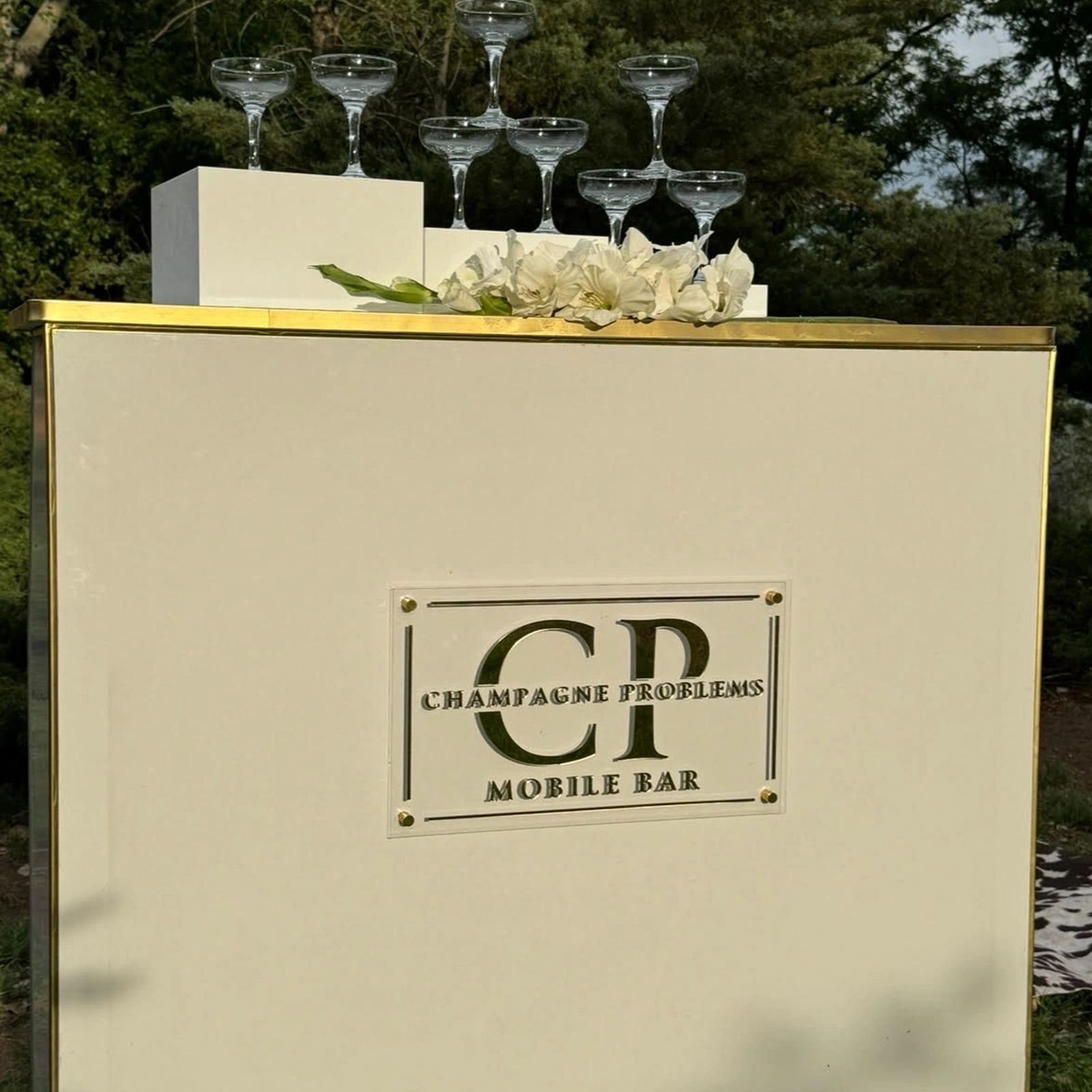 The Champagne Problems mobile bar with hanging glassware and a gold monogram