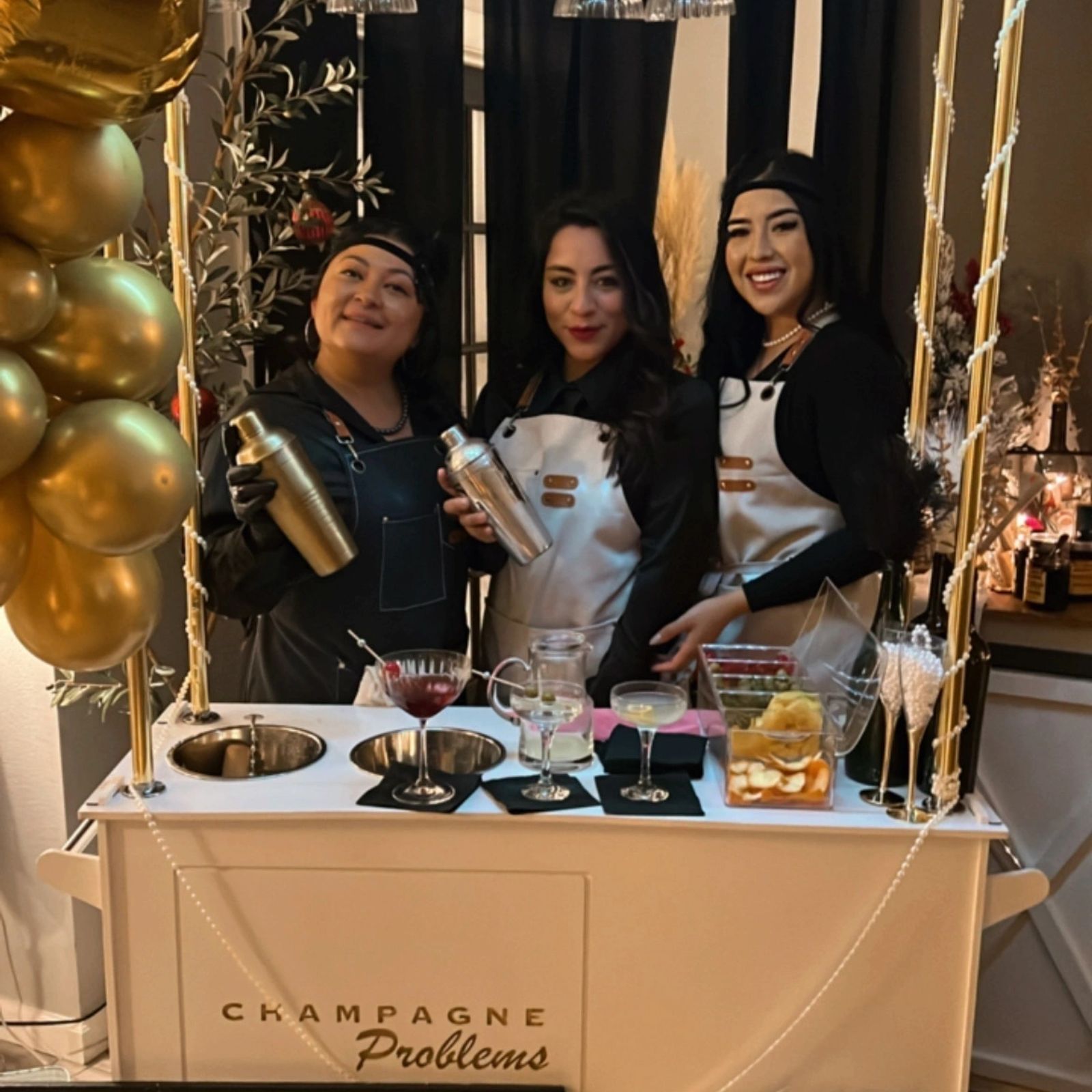 The Champagne Problems bartending crew behind a styled bar with gold balloons