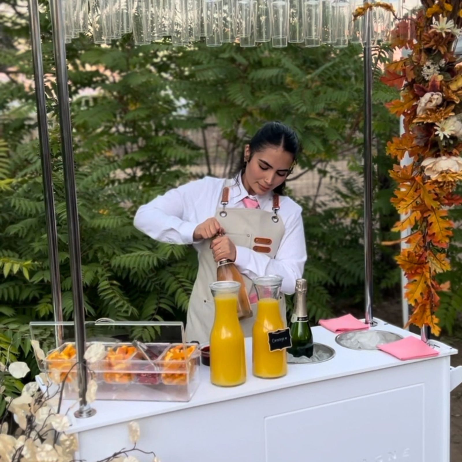 Bartender pouring mimosas at an outdoor autumn event