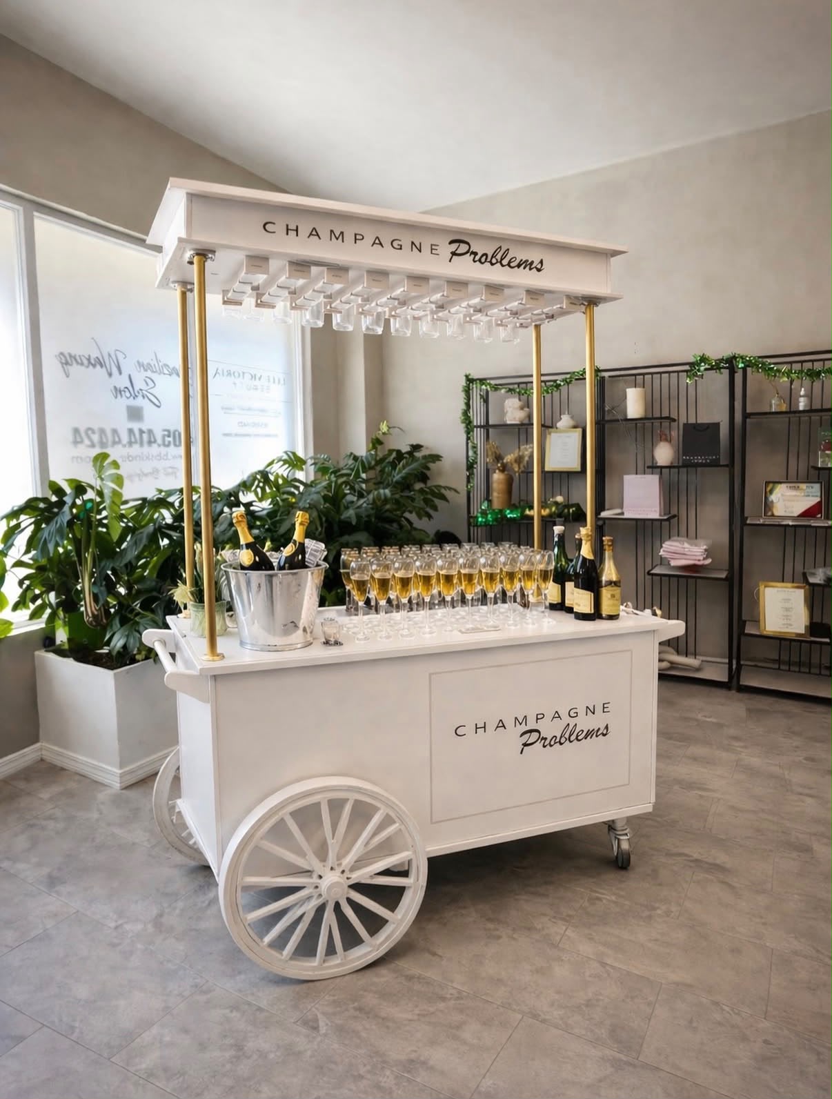 Vintage white-and-gold Champagne Problems bar cart stocked with champagne flutes and chilling bottles